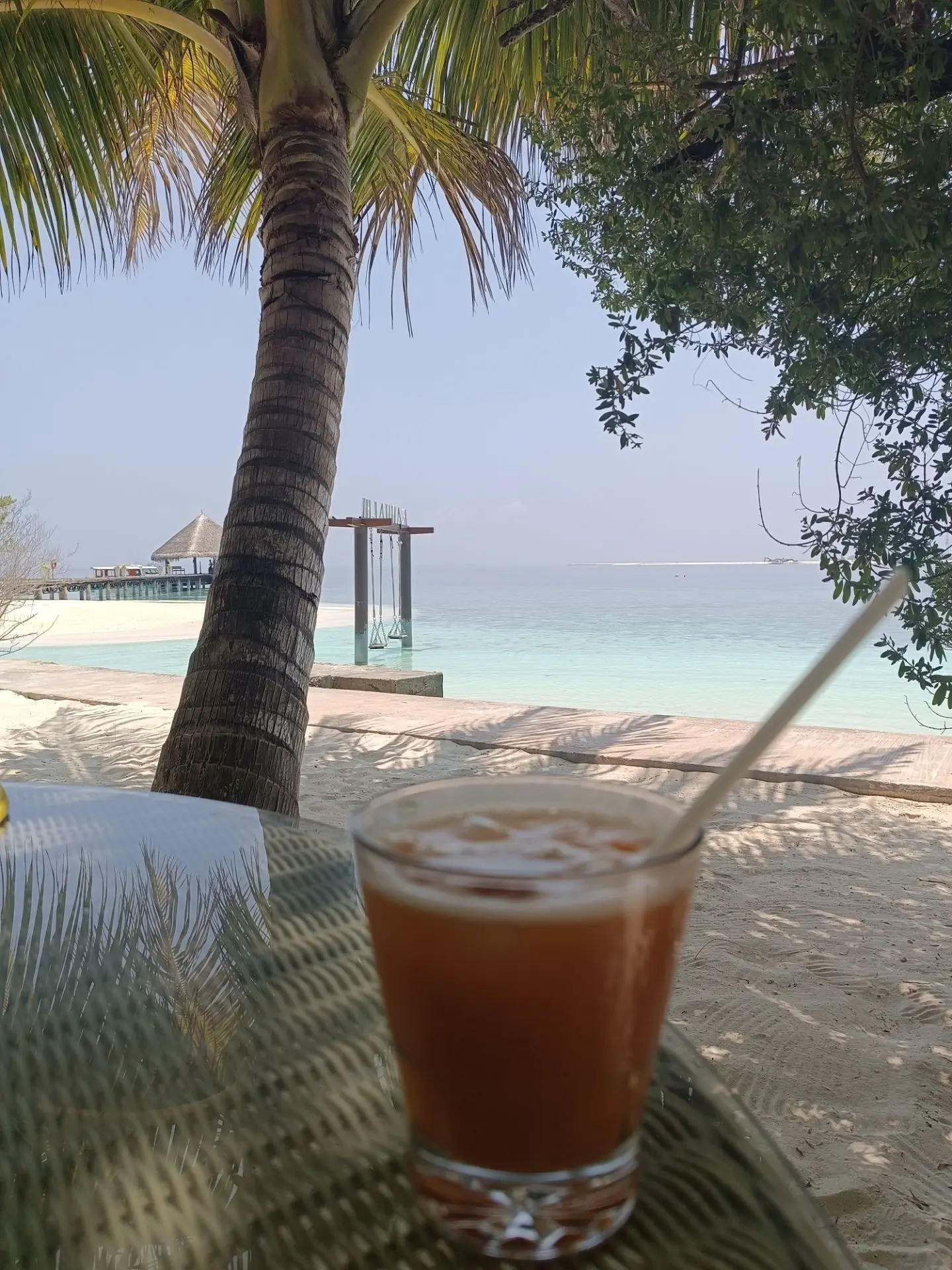 Beachside restaurant tables and chairs under palm trees on a Maldives resort island