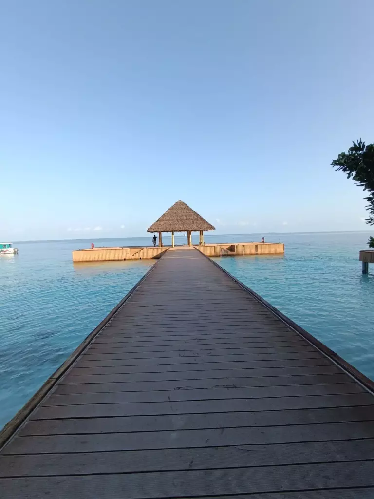 Counting a Country That Will Not Hold Still: How Many Islands the Maldives Has 7 Small palm-covered island with a jetty seen across shallow turquoise water in the Maldives