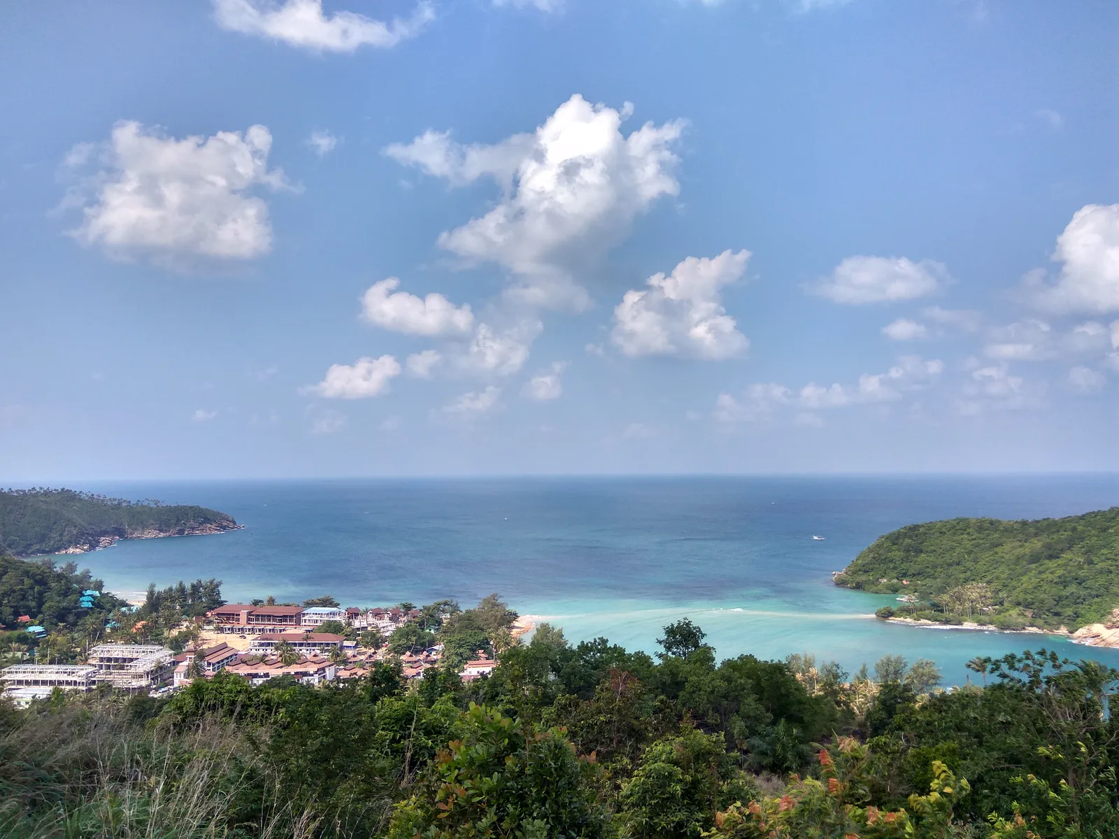 View over a bay with a village, headlands and forested hills