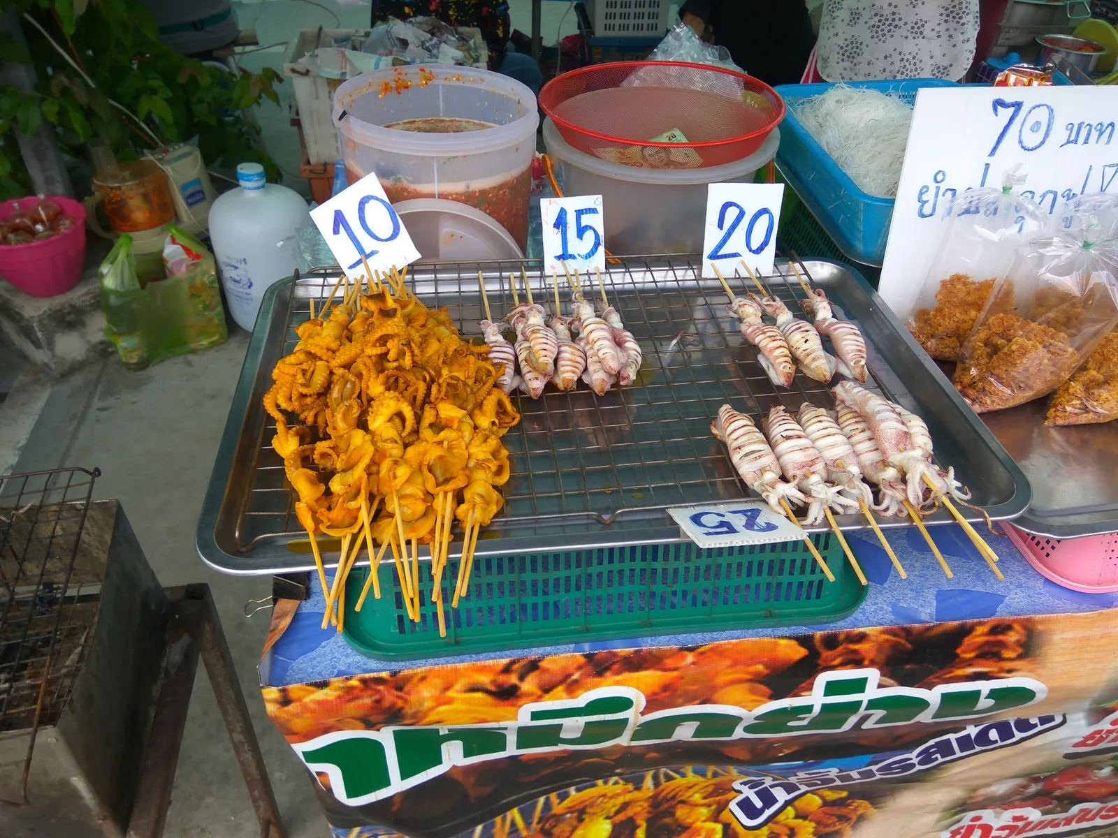 Thai street food stall with grilled skewers and handwritten price cards